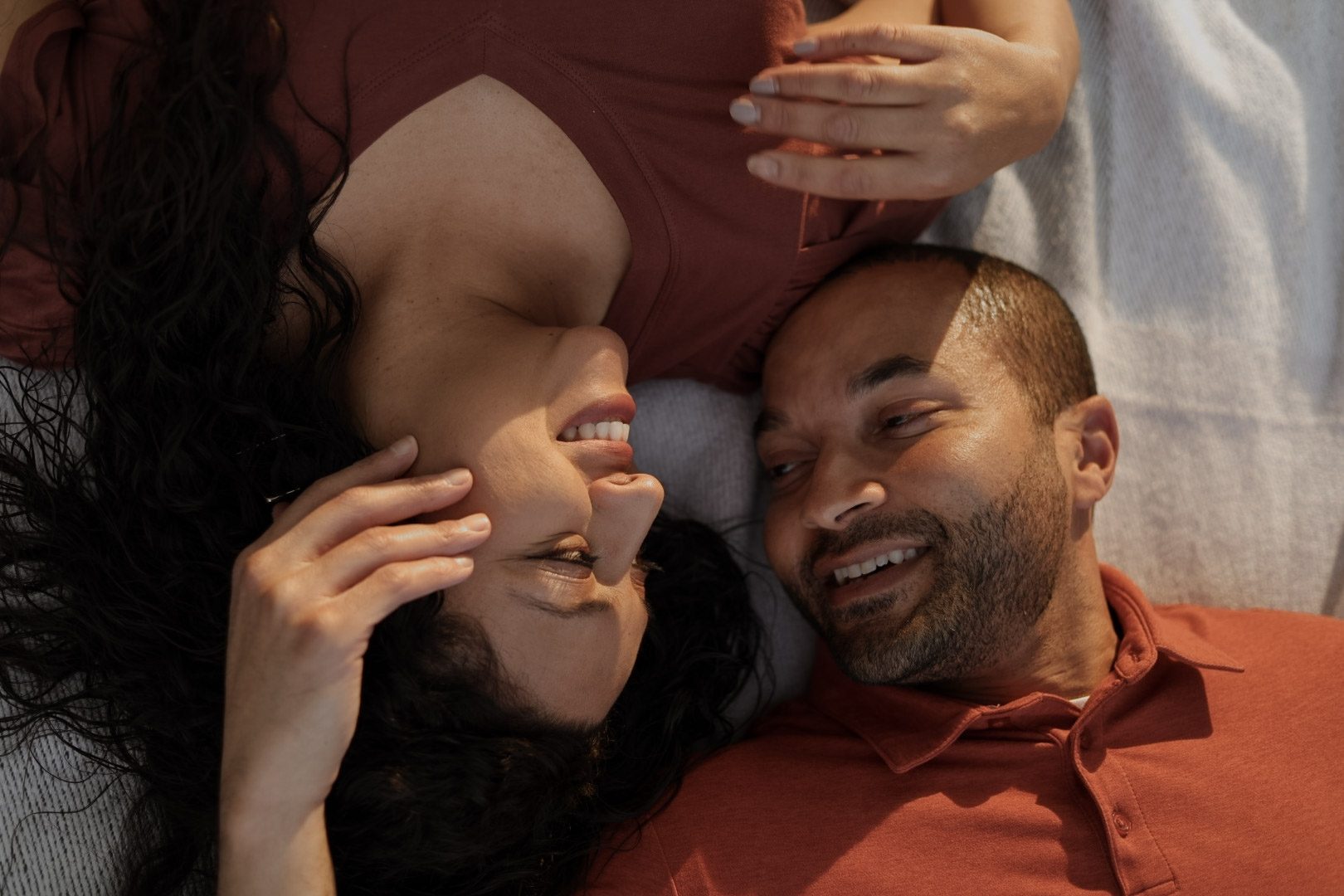 Couple lying side by side in warm evening light, laughing